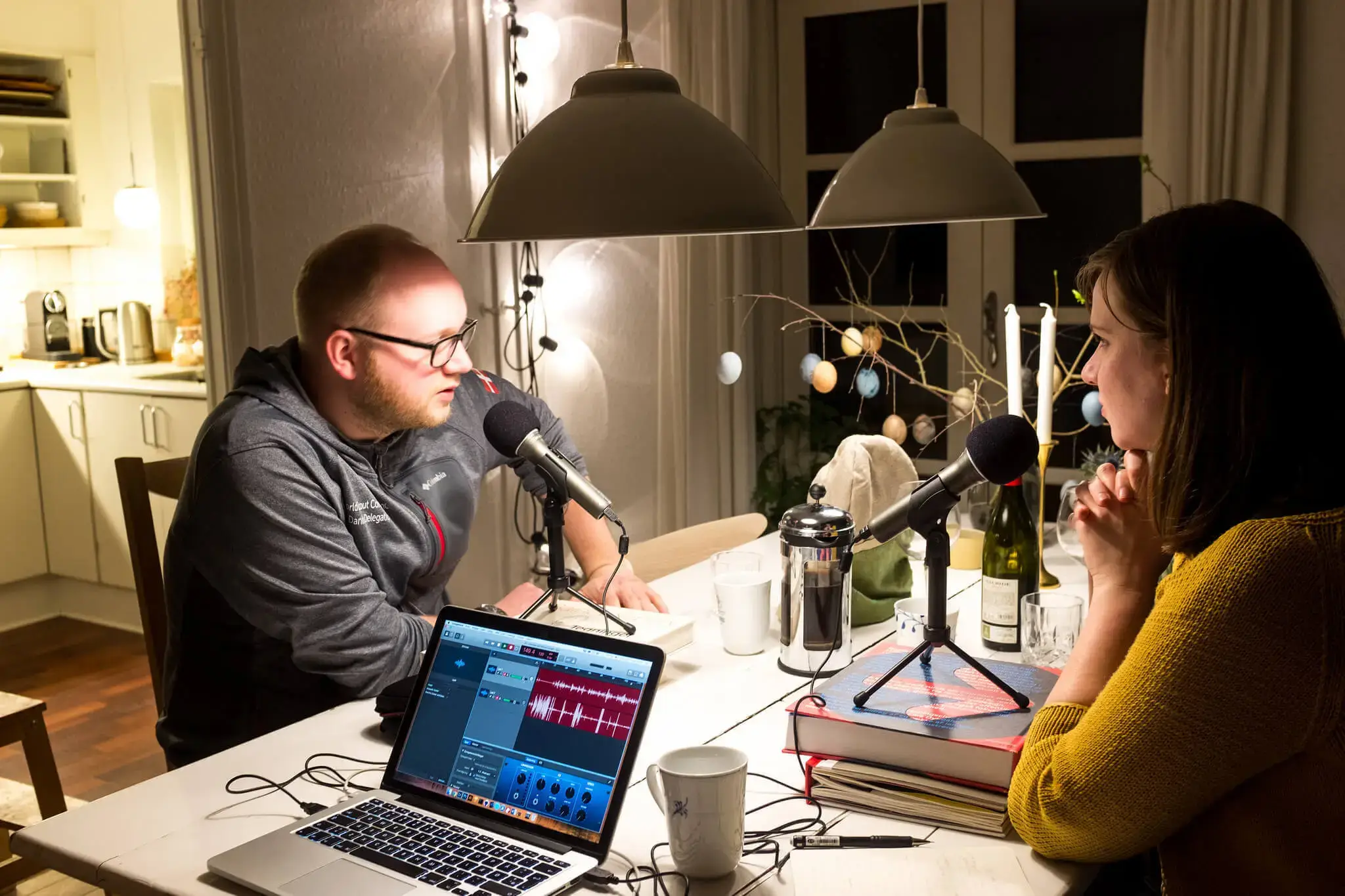 2 persons sitting in a living room recording a podcast