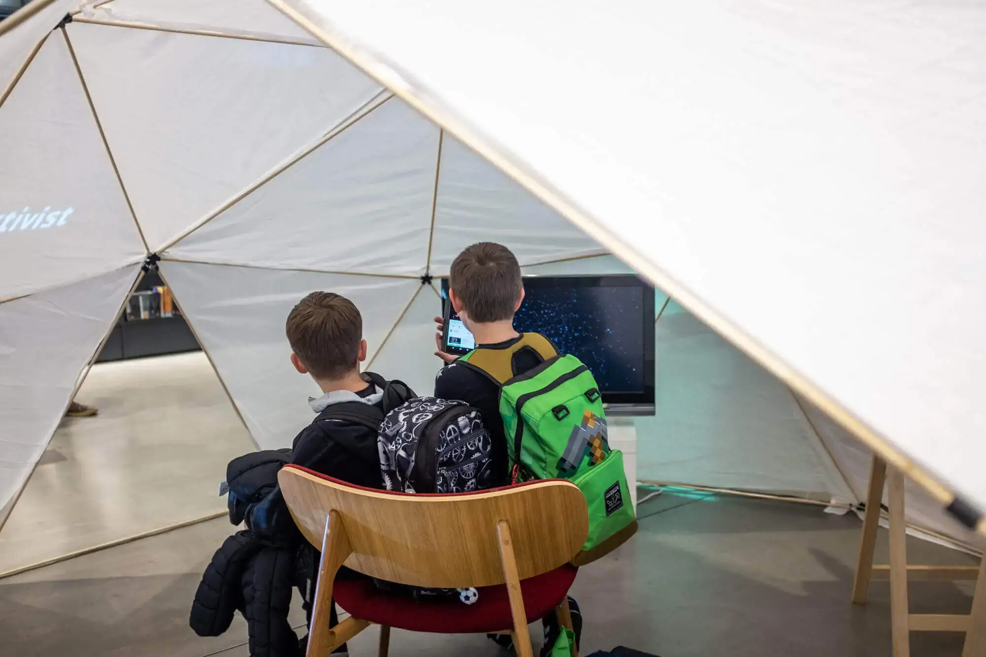 2 children sharing 1 chair inside the filter dome