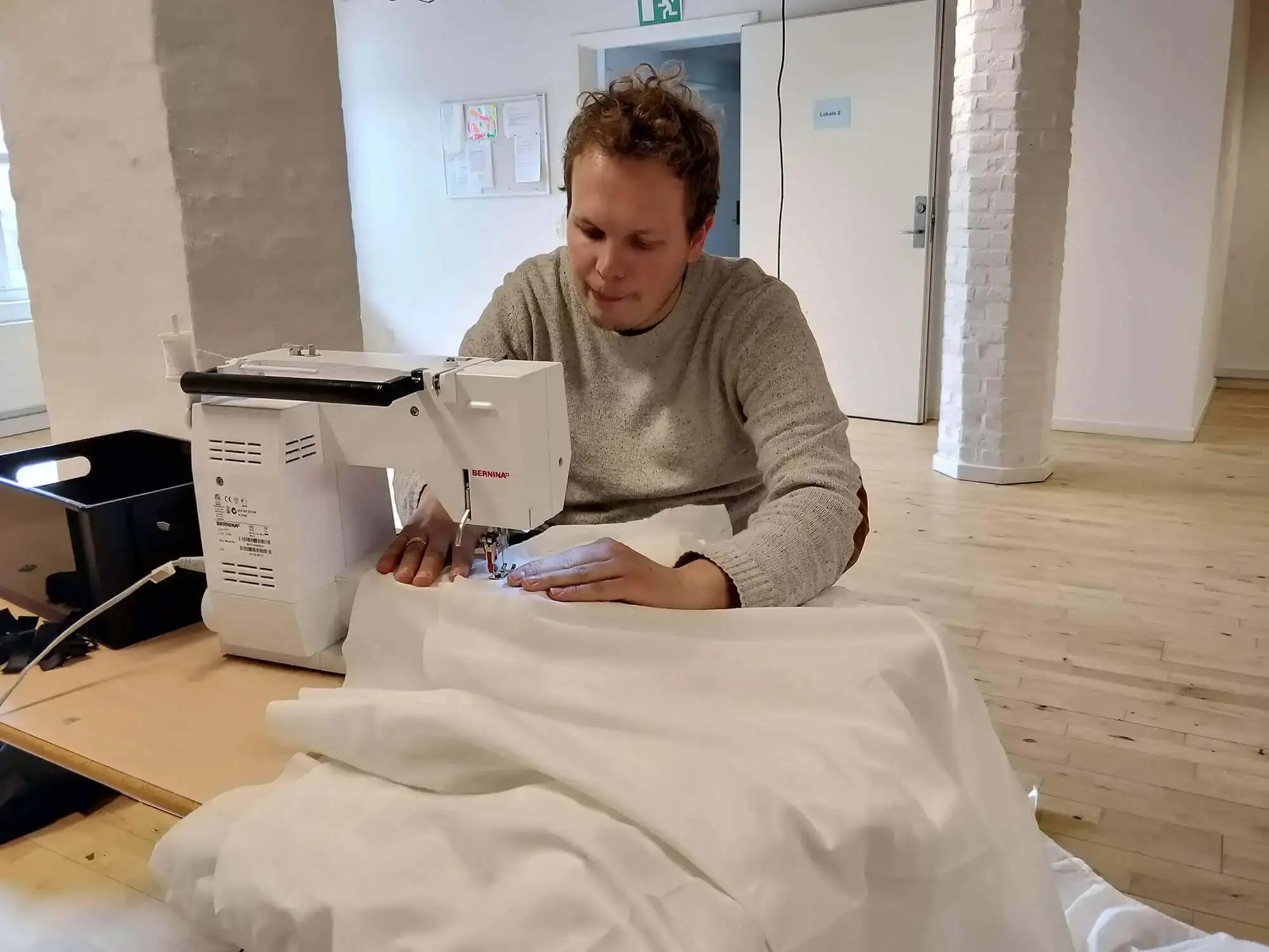 A man (myself) sewing a big sheet on a sewing machine
